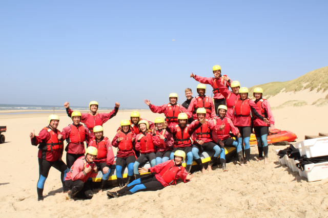 groep mensen met gele helmen en reddingsvesten op het strand